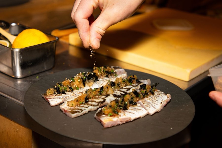 A chef garnishing a seafood dish